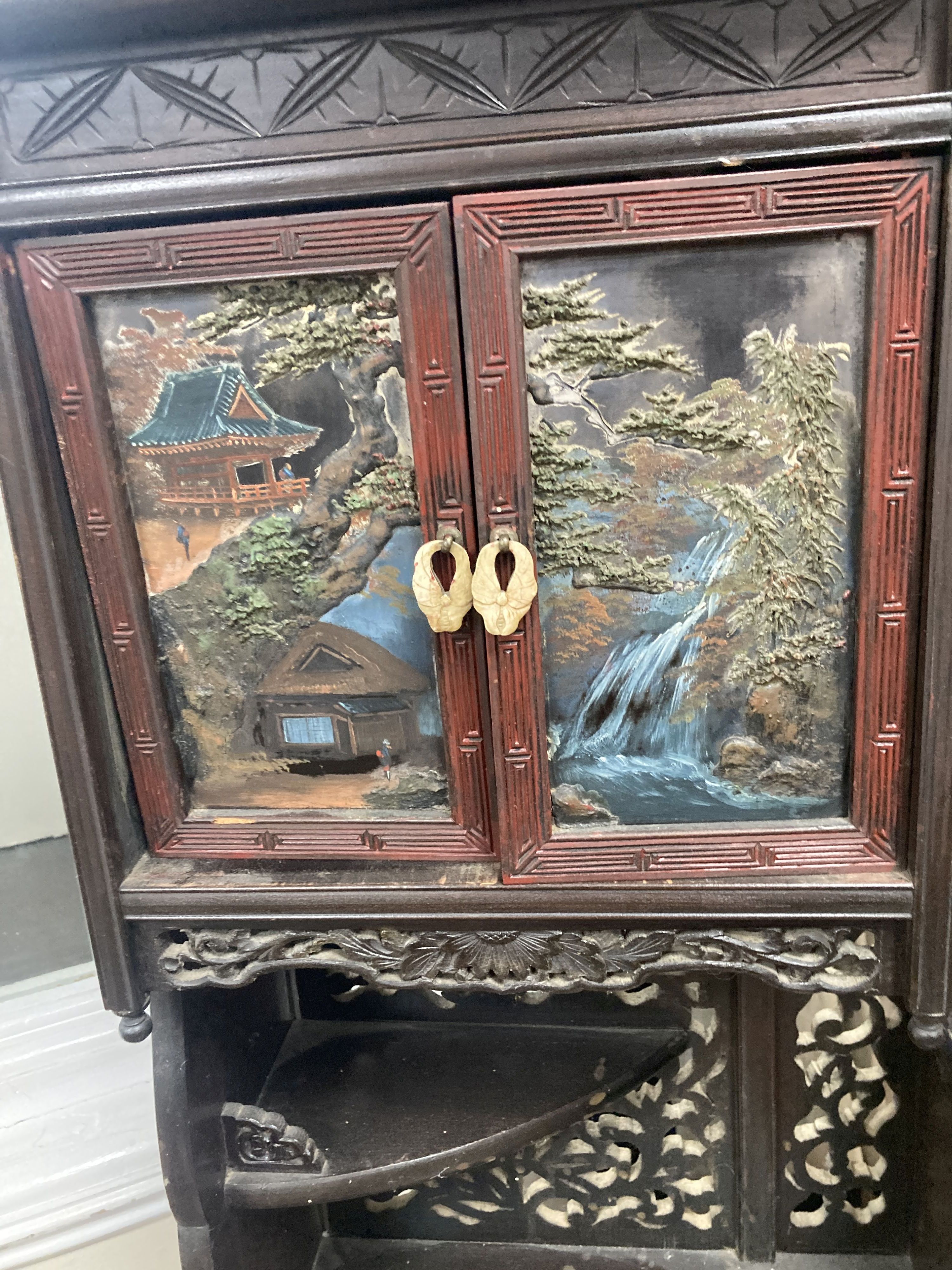 A 20th century Chinese carved cabinet with painted hinged cupboard doors, 79cm height, width 52cm, depth 18cm